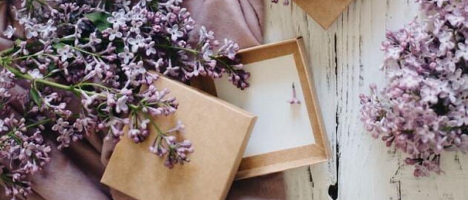 Lila Blumen und offene Geschenkboxen auf lila Tuch