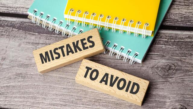 Holzklötze “Fehler, die man vermeiden sollte” liegen auf dem Schreibtisch, zusammen mit Notizbüchern