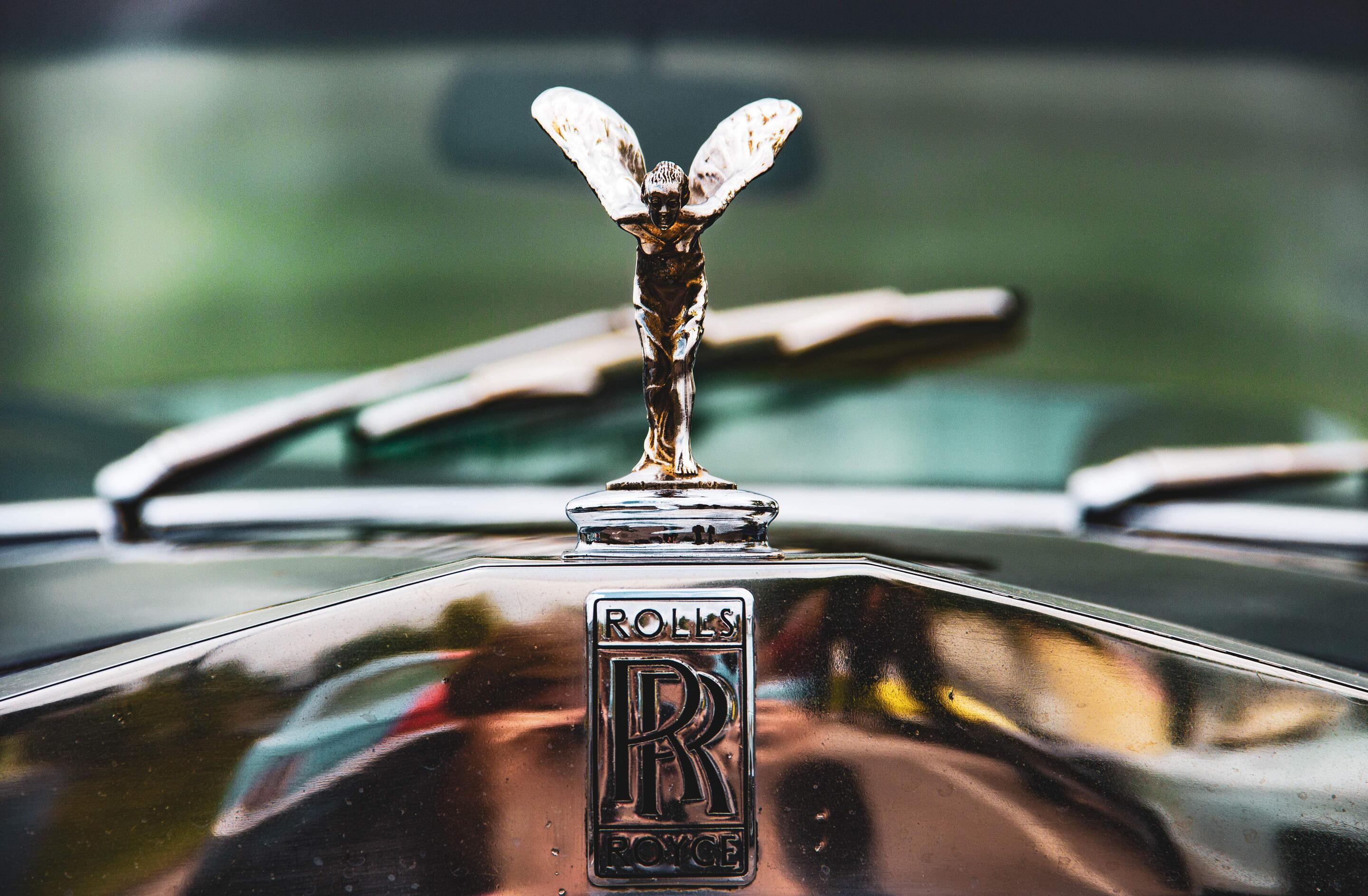 Nahaufnahme des Rolls-Royce-Emblems mit der Kühlerfigur ‘Spirit of Ecstasy’ auf der Motorhaube eines klassischen Fahrzeugs.